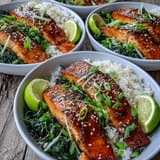 Savory-sweet Miso Glazed Salmon Bowl garnished with nori strips and lime wedges, served alongside fragrant ginger spinach for a balanced meal.