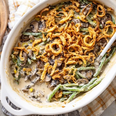 A freshly baked Green Bean Casserole topped with crunchy onions, served on a wooden holiday table.