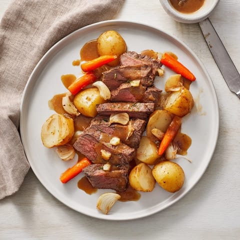 Tender Beef Pot Roast with carrots and potatoes served on a platter, smothered in rich, savory gravy for a hearty family dinner.