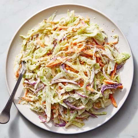 Bright bowl of creamy Coleslaw with shredded green cabbage, carrots, and a tangy, homemade dressing.