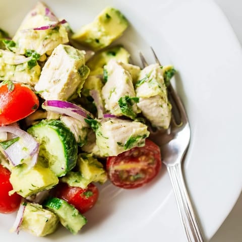Homemade avocado chicken salad served in lettuce cups, garnished with lime and cilantro.  