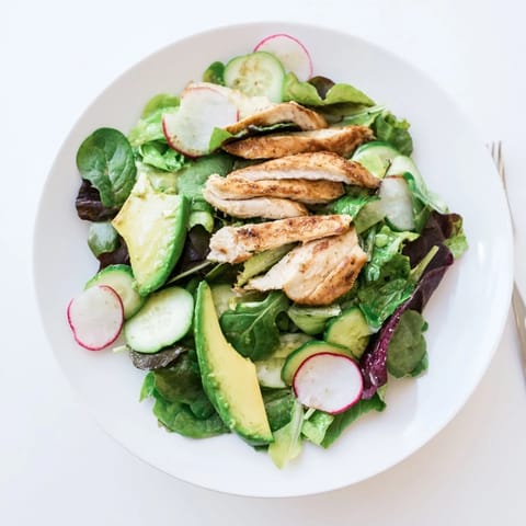 Freshly grilled chicken breast slices rest atop vibrant mixed greens, crisp cucumber, and peppery radish in this Spring Detox Chicken Salad, drizzled with bright lemon vinaigrette.  