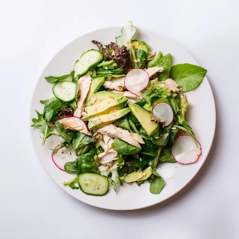 This Spring Detox Chicken Salad features tender grilled chicken, creamy avocado slices, and colorful vegetables tossed in a zesty lemon dressing, served in a rustic white bowl.  
