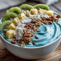 Vibrant blue spirulina smoothie bowl overflowing with fresh tropical fruit.